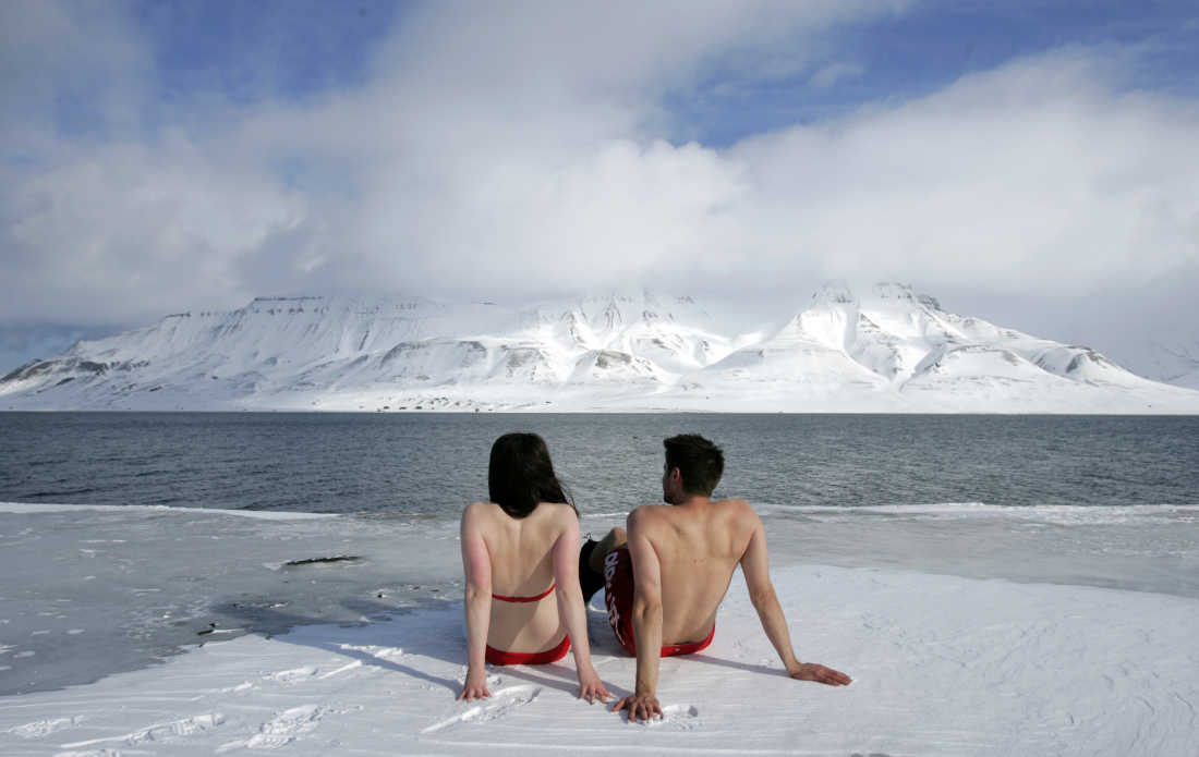 Climate activists Lesley Butler and Rob Bell "sunbathe" on the edge of a frozen fjord in the Norwegian Arctic town of Longyearbyen